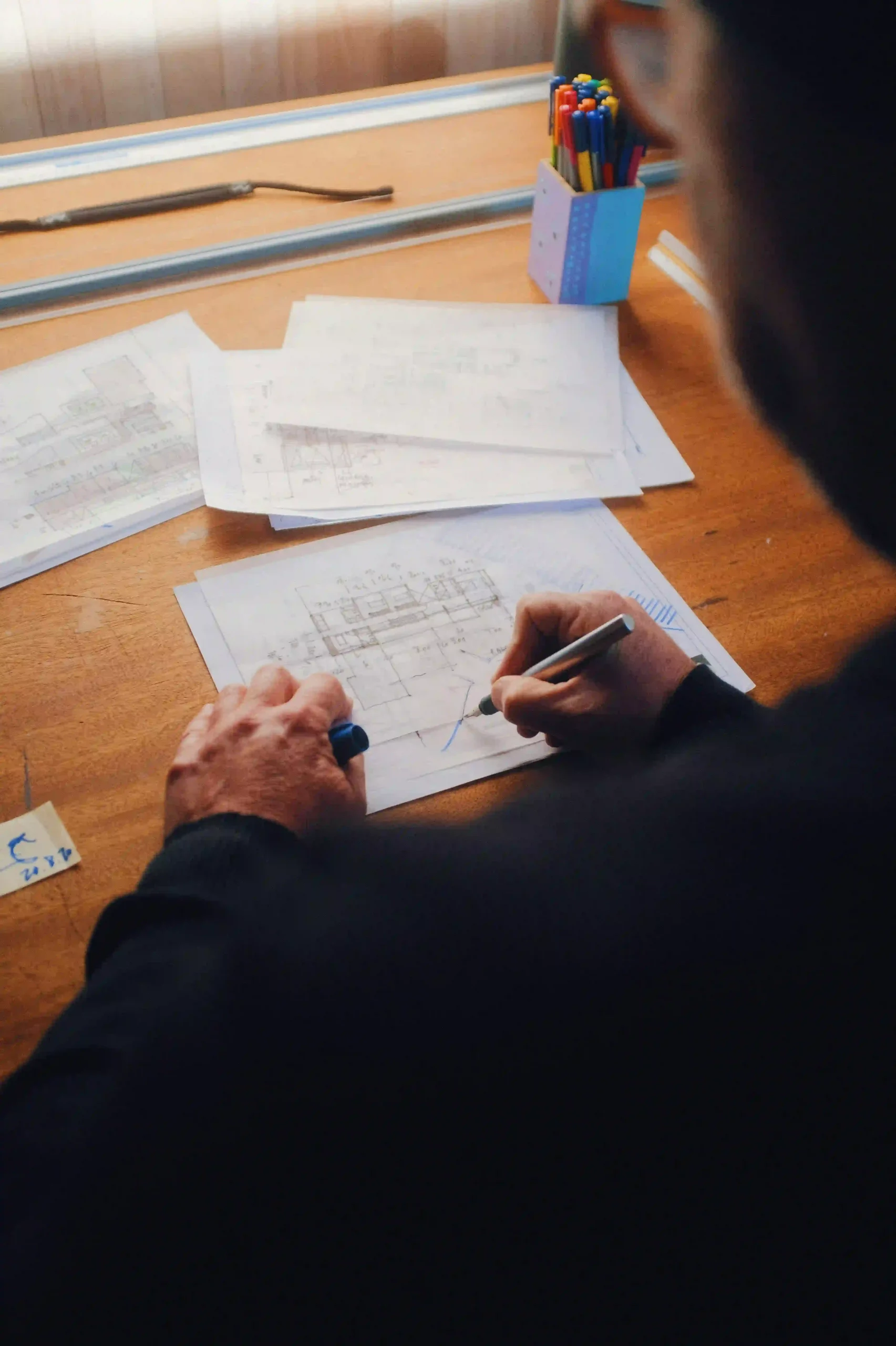 A man with a black shirt is sketching a 3D printing object on a piece of sheet